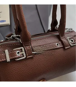 Close-up of brown pebbled leather texture with white stitching and silver hardware detail