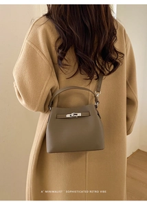 Detail of grey textured leather bucket bag with metal turn-lock on wool coat