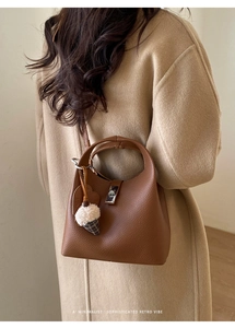 Detail of lychee textured leather handbag with metal lock and plush ice cream charm
