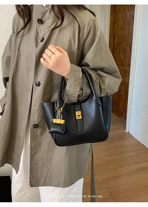 Detail of minimalist black matte leather tote bag with golden twist lock and mini pouch