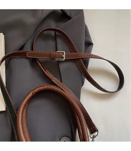 Detail of brown litchi leather bag with white contrast stitching and silver buckle