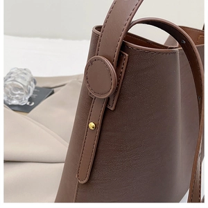 Detailed close-up of dark brown lychee pattern leather bucket bag with metal rivet hardware