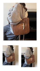 Detail view of brown leather tote bag with stylish wooden beads and metal brand plaque