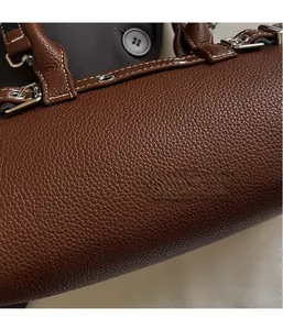 Close-up of brown litchi grain leather bag showing white stitching and silver hardware