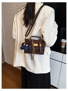 Detail view of vintage dark brown crossbody bag with metal logo and cute bear charm