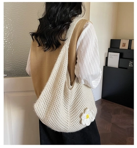 Close-up of beige crochet tote bag featuring white daisy accents and intricate mesh knit texture
