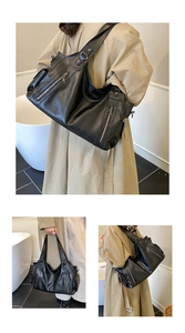 Detail of black soft leather tote with functional silver zippers and multiple pockets