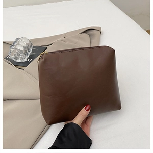 Detail of dark brown leather textured zipper pouch with natural grain and metallic finish
