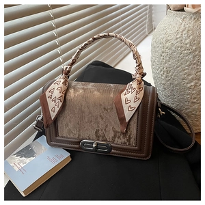 Detail einer braunen Tasche mit einem Seidenschal mit Herzmuster am Tragegriff