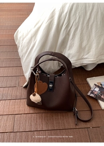 Detail of dark brown lychee leather bucket bag with silver twist lock and heart charm