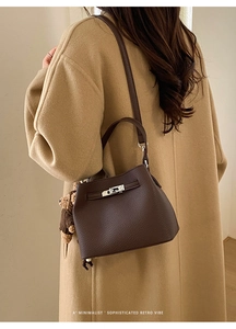 Detail of vintage brown pebble leather bucket bag with silver lock and plush bear charm