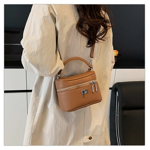 Detail view of a caramel brown lychee texture box bag with silver hardware on a model