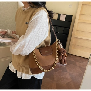 Close-up of retro color-block quilted shoulder bag with gold chain and plush bear charm