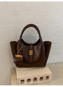 Detail of retro dark brown handbag with golden twist lock and a mini bag charm
