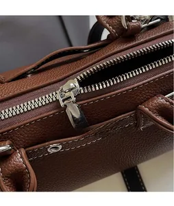 Close-up of premium silver metal zipper on a textured brown leather shoulder handbag