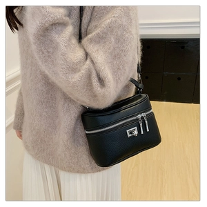 Detail of black pebbled leather box bag showing silver metal lock and zip closure