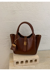Detail view of a retro brown leather handbag with gold twist lock and side wing structure