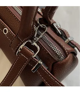 Detail of dark brown pebble leather baguette bag with silver hardware and contrast stitching