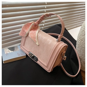 Nahaufnahme einer rosa Wellentextur-Handtasche mit silbernem Drehverschluss und Schal
