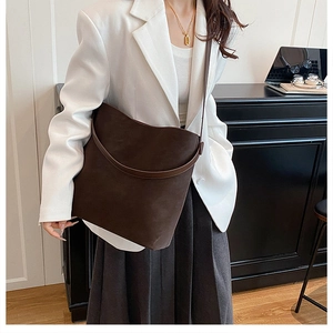 Dettaglio della texture in pelle opaca e tracolla sottile della borsa tote marrone