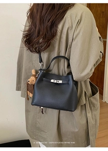Detail of black lychee grain leather bucket bag with silver lock and bear charm