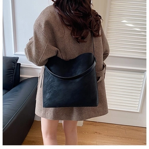 Close-up of a black matte tote bag showing the texture and strap in a modern home setting