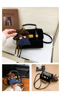 Detail of a black patchwork backpack with a gold fashion plate and a cute plush bear charm
