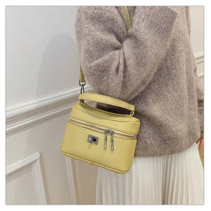 Detail of a bright yellow box handbag with pebble leather texture and silver hardware
