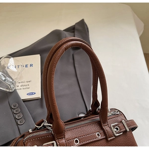 Detailed close-up of brown lychee leather bag with white stitching and silver hardware