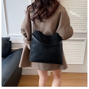 Modern black frosted tote bag shown on shoulder in a minimalist interior setting