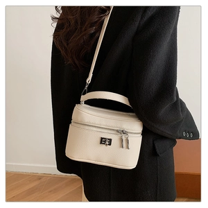 Detail of a beige lychee leather mini vanity bag with silver hardware and crossbody strap