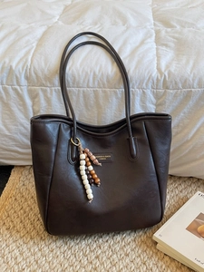 Large dark brown leather tote bag with elegant beaded charm and fashion label tag