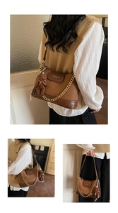Detailed view of a retro brown leather crossbody bag with chain and plush bear charm