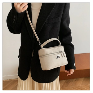 Detail of a creamy beige lychee grain leather box bag featuring silver-tone metal hardware