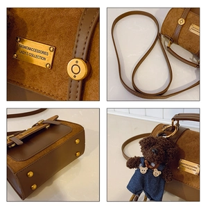 Detail of vintage brown suede crossbody bag with gold logo plate and bear pendant charm