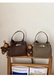 Detail of lychee pattern leather bucket bag with silver twist lock and bear charm