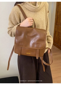 Dettaglio dello zaino retrò in pelle marrone con placca logo dorata e patta chiusa
