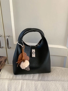 Black lychee leather bucket bag with silver turn-lock closure and decorative charms