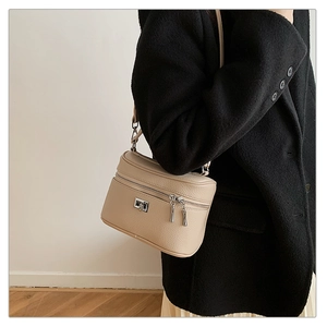 Detail of beige lychee pattern leather crossbody bag with dual silver zippers