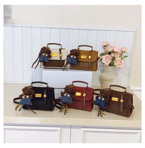 Detail view of five retro college style backpacks in various colors with cute bear charms