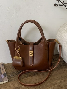 Retro brown bucket bag with gold clasp and adjustable strap on a rustic wood surface
