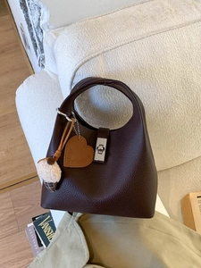 Chocolate brown litchi pattern leather bucket bag with silver lock on white sofa