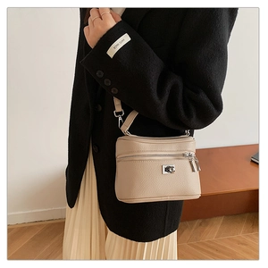 Detail of apricot pebbled leather crossbody bag with dual zippers and silver metal lock