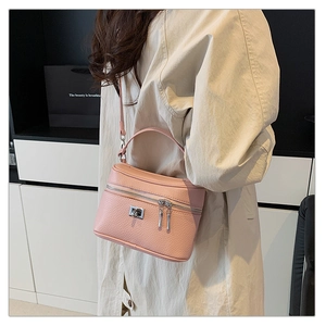 Close-up of pink litchi grain leather texture and metallic clasp on a box-style handbag