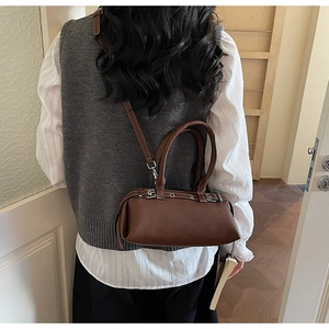 Brown leather baguette bag with silver buckles shown as a shoulder bag on a model