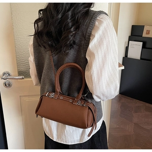 Macro shot of brown pebble grain leather bag with dual handles and silver hardware