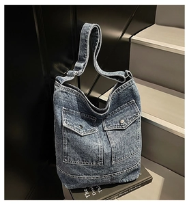 Detail of blue denim tote bag featuring vintage wash texture and double cargo pockets