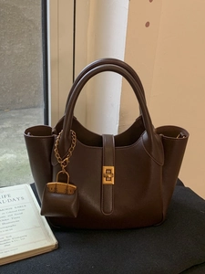 Minimalist dark brown tote bag with gold twist lock and a matching mini charm