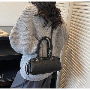 Detailed view of black pebbled leather baguette bag with silver buckles and adjustable strap