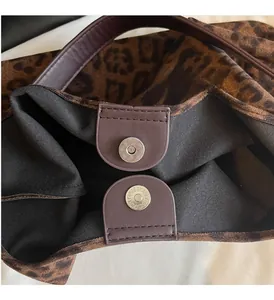 Dettaglio della borsa leopardata con chiusura magnetica e finiture in pelle marrone